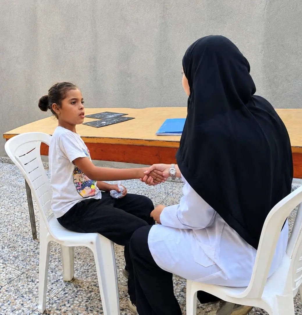 طفلة على كرسي أمام سيدة تجلس بالقرب منها