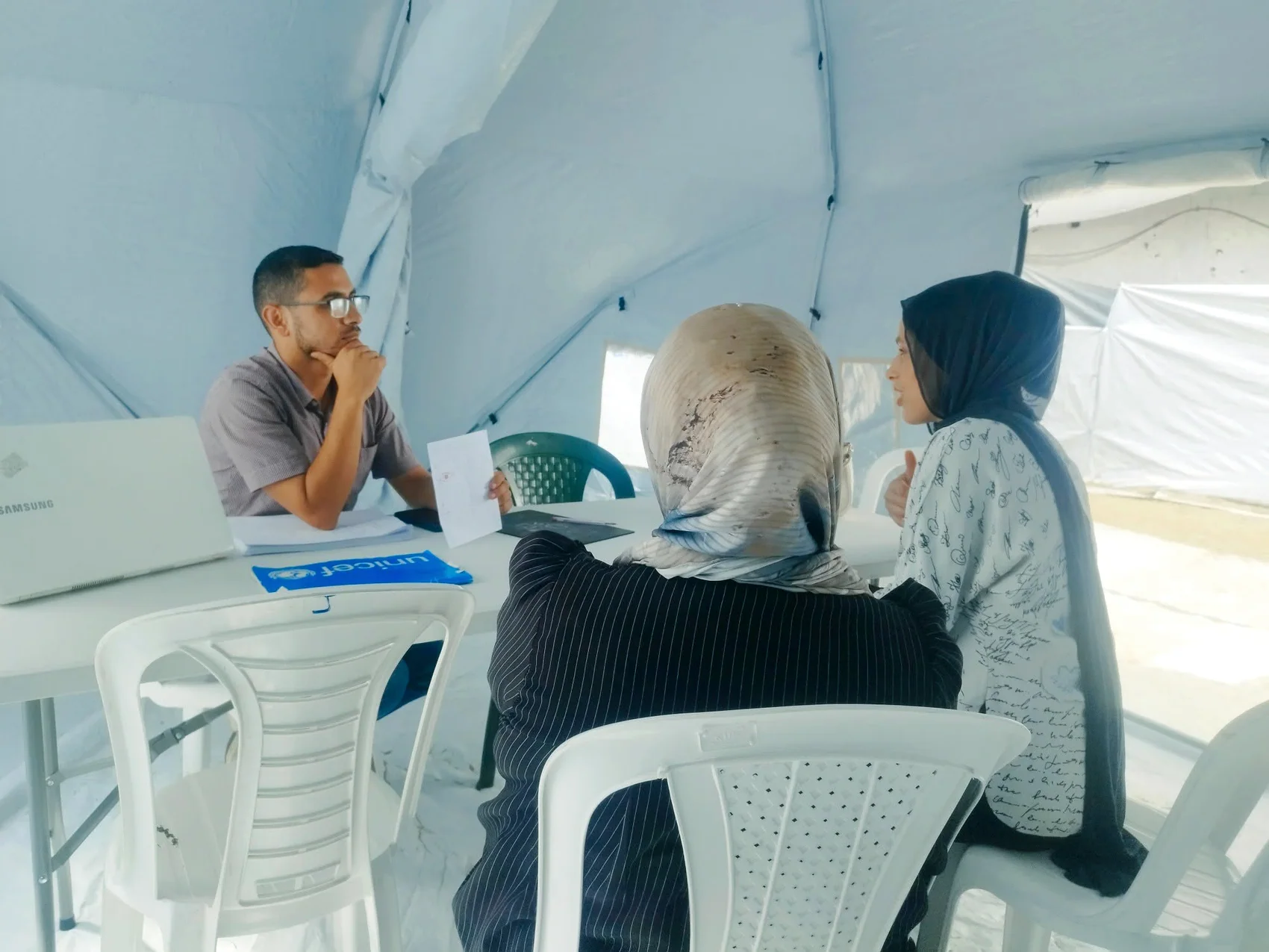 ثلاثة بالغين يتحدثون حول طاولة في مساحة عمل مغطاة